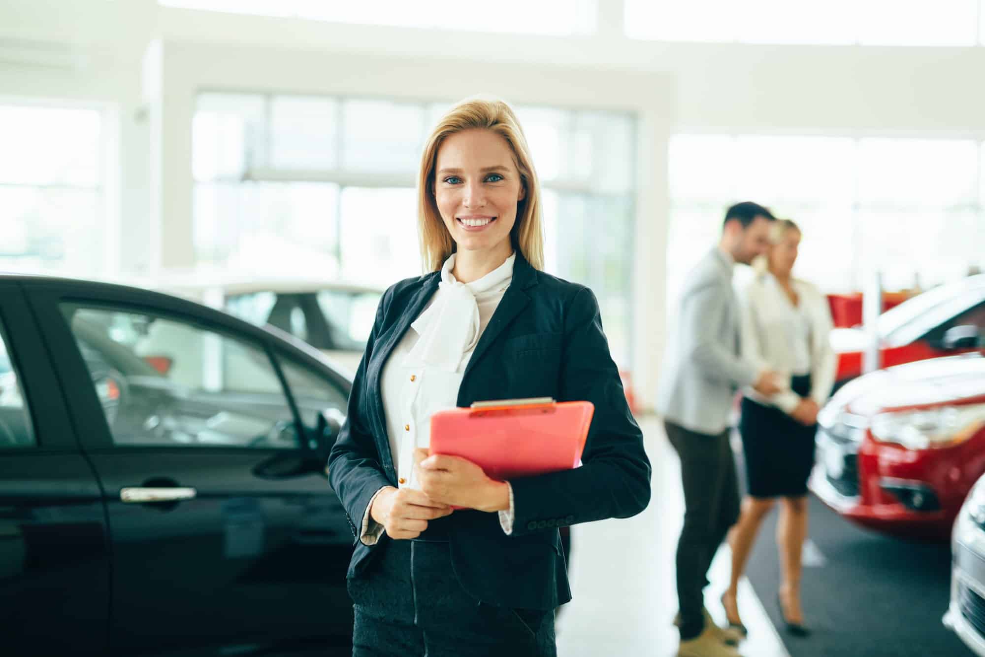 Young female car sales consultant working in showroom